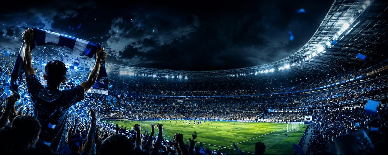 A fan raising a scarf over a packed stadium at night